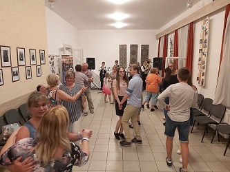 Táncoló vendégek a Német Ház termében, a falon tárlókkal.