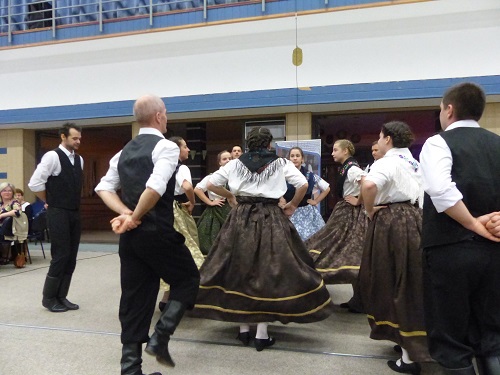 Sváb népviseletben táncoló párok egy terem közepén.