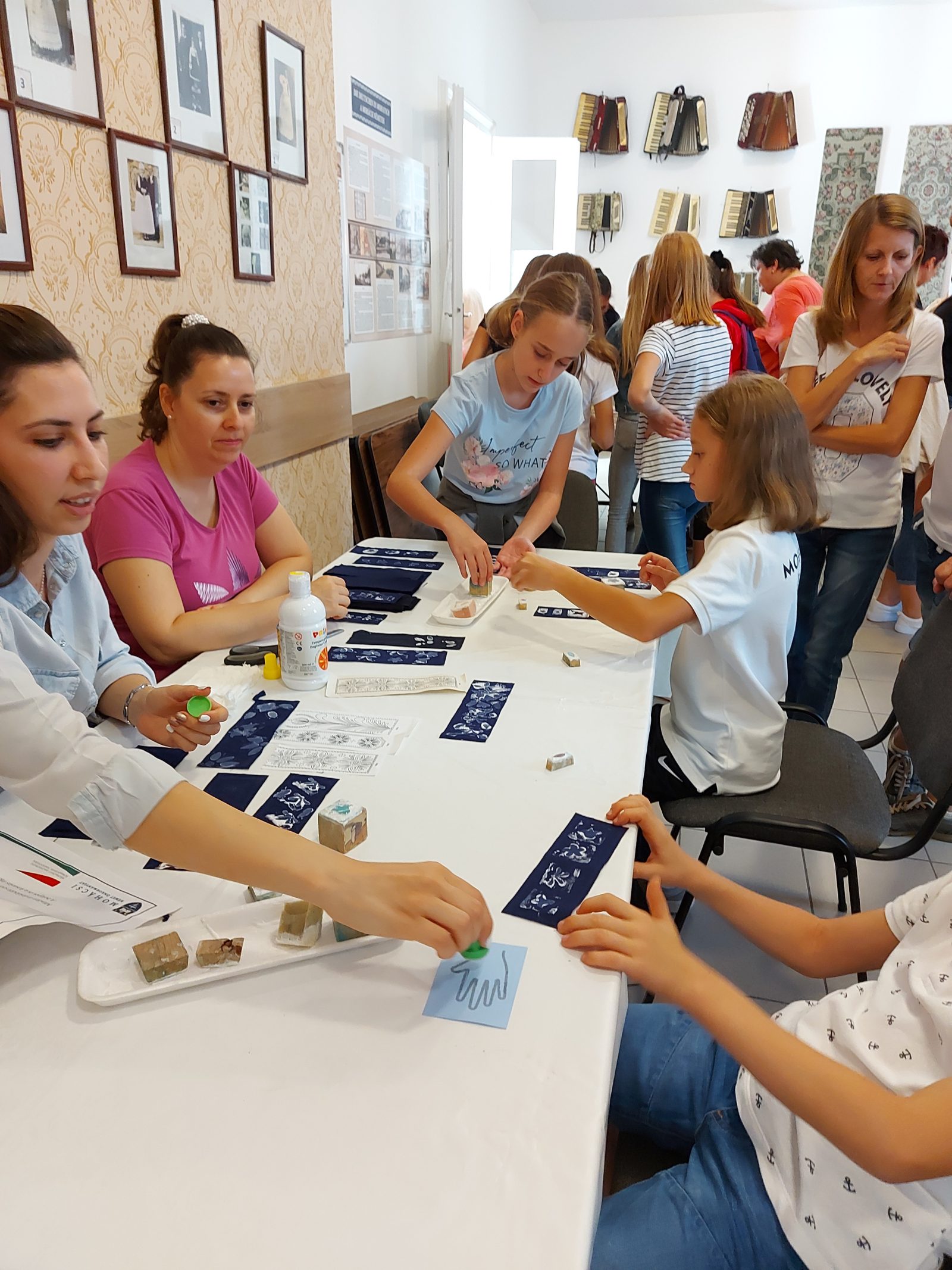 Résztvevők képeket és kártyákat raknak fel egy táblára a kiállítóteremben.