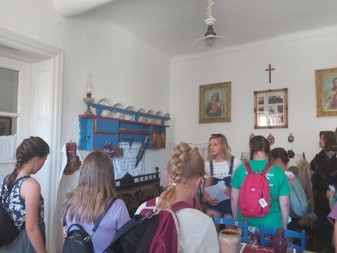 Hátizsákos fiatalok egy szobában, a falon szentképek és feszület.
