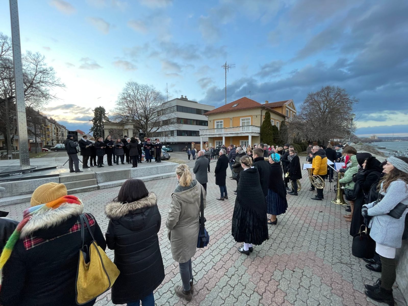 Tömeg sétál a folyóparti úton egy szabadtéri megemlékezésen.