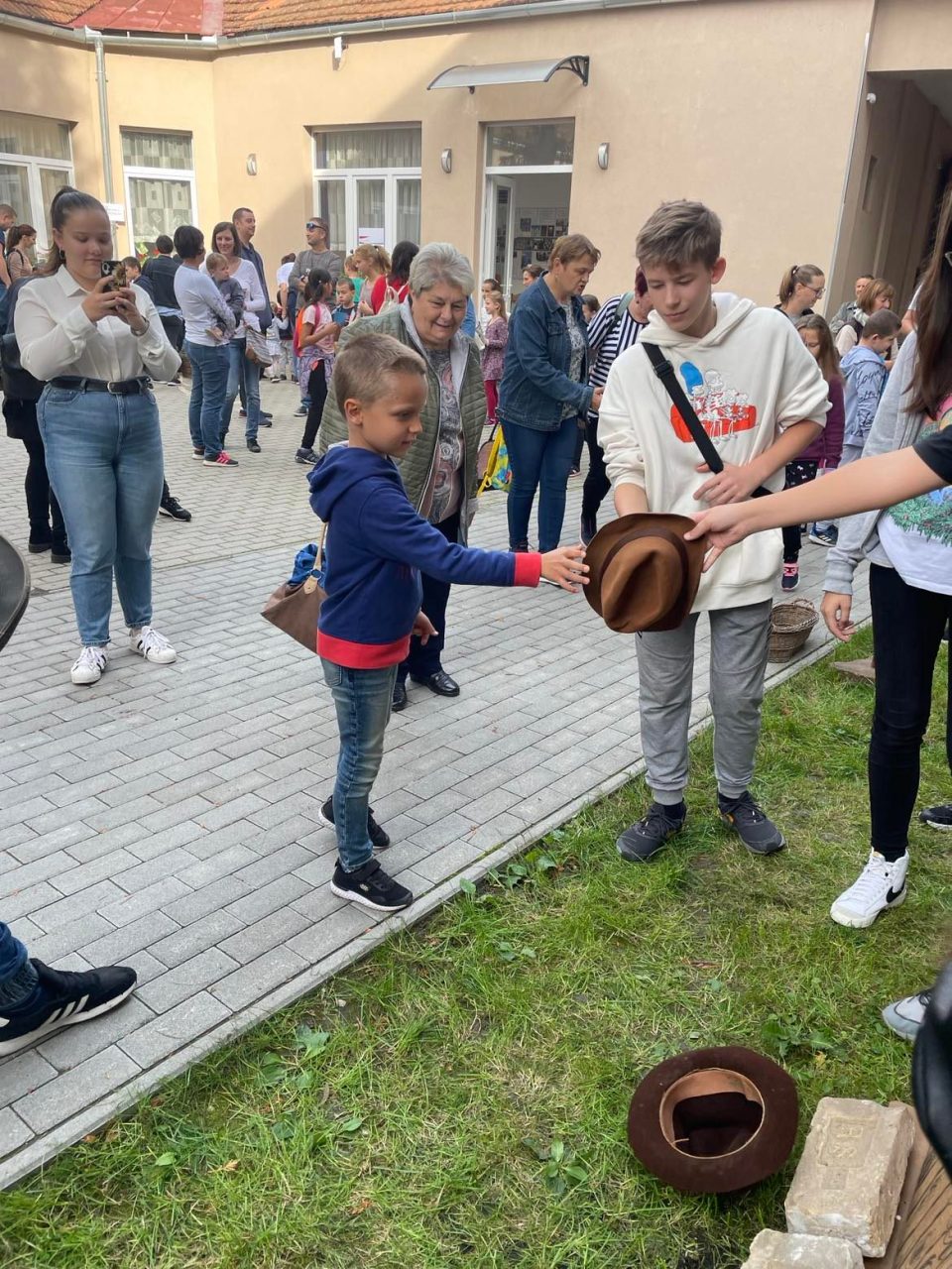 Gyerekek kalapos ügyességi játékot játszanak a szabadtéri rendezvényen.