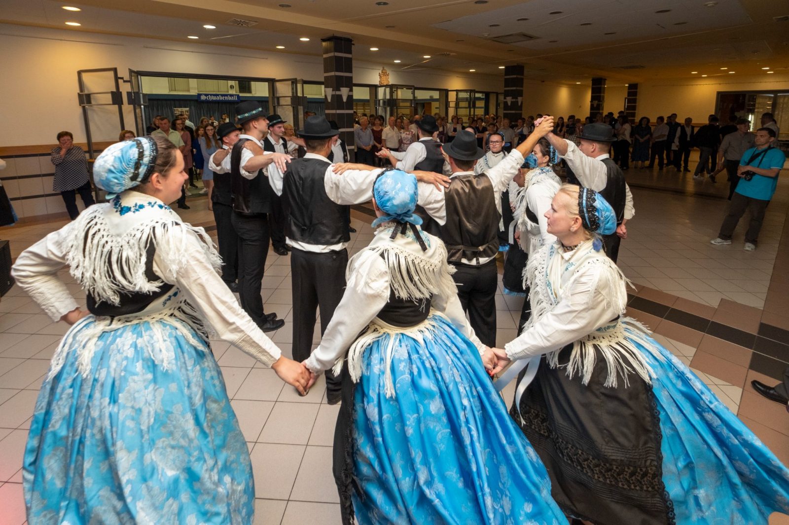 Zöld pólós gyerekek és fiatalok harmonikákkal a pavilon alatt.