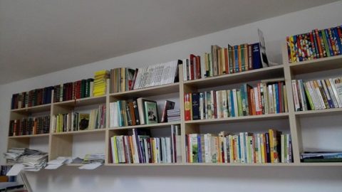 Fehér polcok könyvekkel egy világos könyvtárszobában.