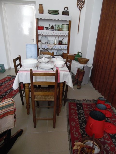 Terített asztal a konyhában, a polcon porcelánedények.