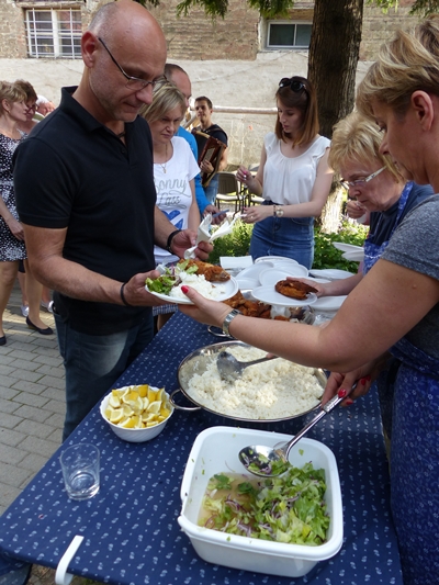 Vendégek halételt szednek a tálalóasztalnál a szabadban.