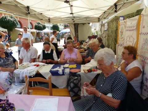 Sátor alatt asztaloknál ülő látogatók kézműveskednek a fesztiválon.