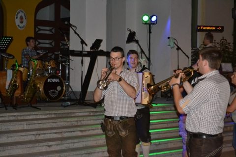 Bläser in Lederhosen spielen beim abendlichen Straßenball.