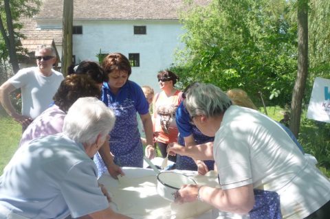 Frauen kneten Teig um eine Schüssel im Freien.