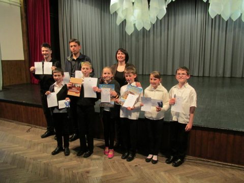 Ausgezeichnete Kinder und ihre Begleiter mit Urkunden vor der Bühne.