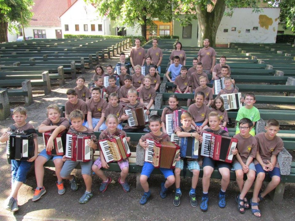 Kinder in braunen T-Shirts mit Akkordeons auf der Tribüne der Freilichtbühne.