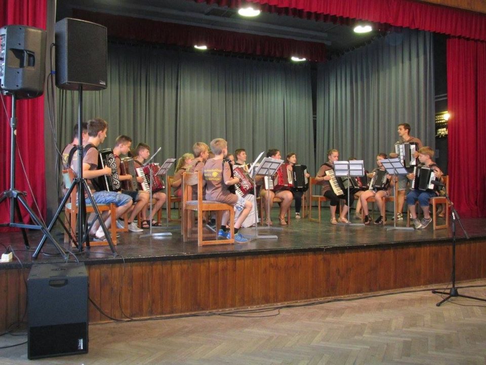 Harmonikás gyerekzenekar próbál a színpadon.