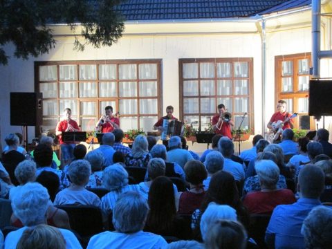 Kapelle spielt vorn im Saal, davor das sitzende Publikum von hinten.
