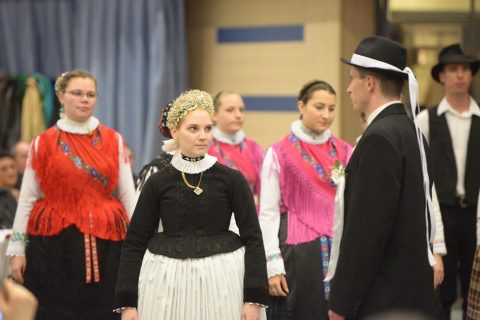 Tänzer in schwäbischer und schokatzischer Tracht in einem Ballsaal.