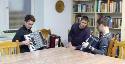 Két fiatal harmonikázik egymással szemben a könyvtárban.