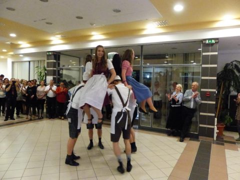 Tänzer in Tracht in der Saalmitte, ein Mann hebt seine Partnerin in die Luft.