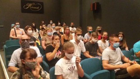 Maszkot viselő fiatalok ülnek egy nézőtéren.