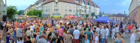 Zsúfolt utcai fesztivál a belvárosban, sátrakkal és nagy tömeggel.