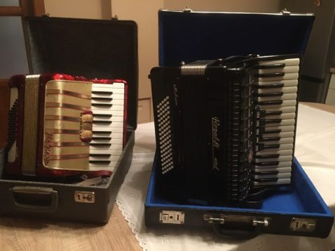 Két harmonika nyitott hangszertokokban egy asztalon.