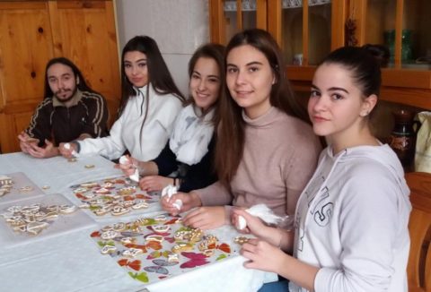 Öt fiatal ül egy asztalnál, előttük kivágott papírfigurák.